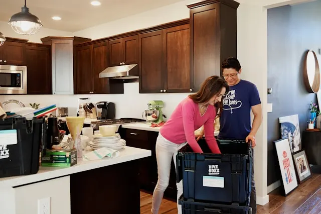 Couple packing items into storage crates while decluttering your home kitchen