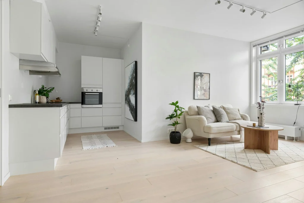 Modern open-plan living room with white kitchen cabinets, beige sofa, and natural light showcasing home decor tips for a stylish space