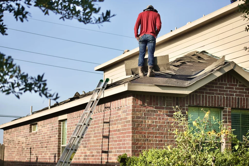 A residential roofing contractor inspecting damaged shingles on a roof, an important step when learning how to choose a roofing contractor.