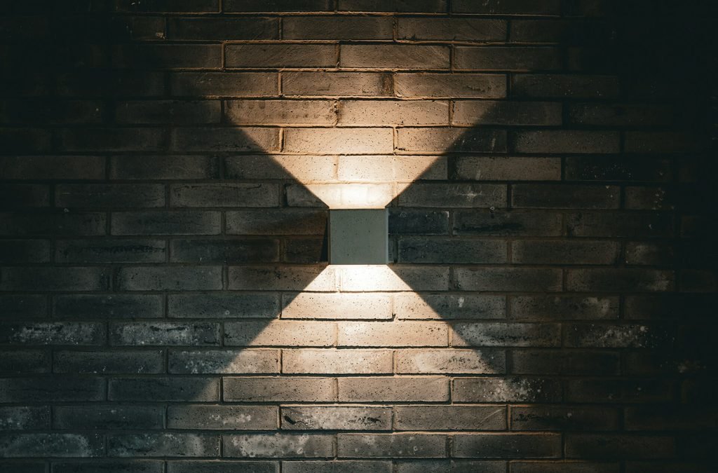 Square wall mounted up downlight fixture showing one of the modern types of outdoor lighting on a brick wall